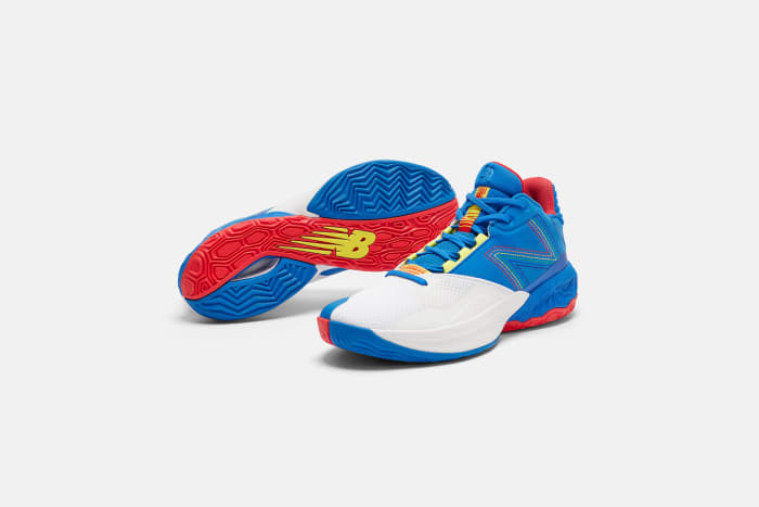 Side view of white, blue, and red New Balance basketball shoes.
